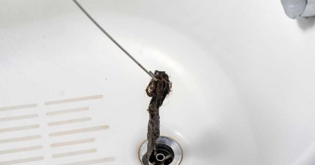 Déboucher une salle de bain à l'aide d'un cintre en fil de fer